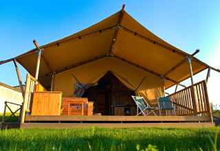 Safaritent 'Tenda 1' in Italië met houten veranda, stoelen en canvasdak onder een blauwe lucht.