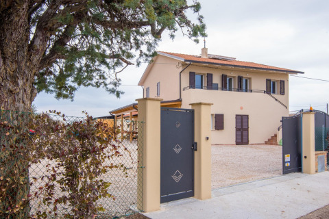 Ingang met zwart hekwerk, boom en villa bij Tenda 1, een safaritentaccommodatie in Italië.