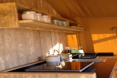 Cucina rustica nella tenda safari Tenda 1 in Italia con mensole in legno, fornello, lavello e sole