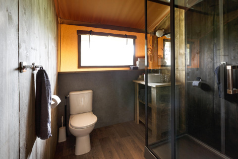 Moderne badkamer met douche, toilet en wastafel in een safaritentaccommodatie in Italië.