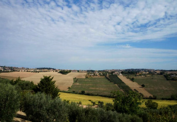 Uitzicht op open velden en dorpjes vanaf safaritent Tenda 1 in Italië onder een deels bewolkte lucht.