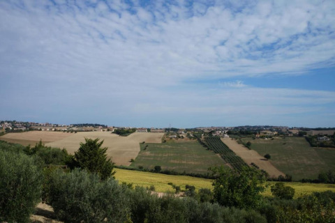 Uitzicht op open velden en dorpjes vanaf safaritent Tenda 1 in Italië onder een deels bewolkte lucht.