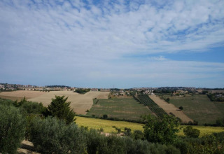 Uitzicht op open velden en dorpjes vanaf safaritent Tenda 1 in Italië onder een deels bewolkte lucht.