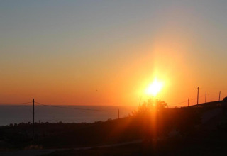 Zonsondergang gezien vanaf safaritent Tenda 1 in Italië, met een rustige horizon en gouden zonlicht.