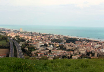 Uitzicht vanaf safaritent Tenda 1 in Italië op een kustplaats, snelweg, gebouwen en zee.