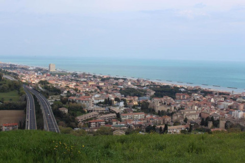 Uitzicht vanaf safaritent Tenda 1 in Italië op een kustplaats, snelweg, gebouwen en zee.