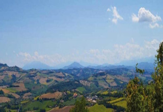 Uitzicht vanaf safaritent Tenda 1 in Italië op groene heuvels, velden en een heldere blauwe lucht.