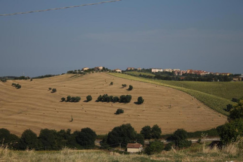 Uitzicht vanaf safaritent 'Tenda 1' in Italië met glooiende velden, bomen en een dorp op een heuvel.