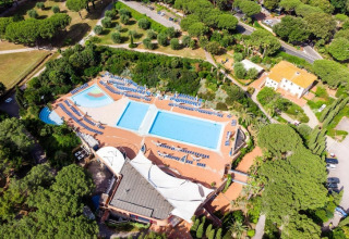 Aerial view of Holiday Resort Riva degli Etruschi in Italy, featuring pools and sun loungers among trees.