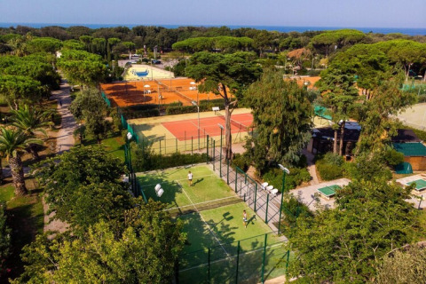 Aerial view of Holiday Resort Riva degli Etruschi in Italy, featuring tennis courts, trees, and the sea beyond.