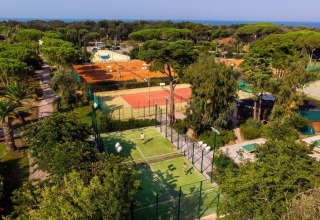 Vista aérea del Holiday Resort Riva degli Etruschi en Italia, con canchas de tenis, árboles y el mar al fondo.