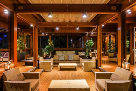 Salón moderno de casa móvil con interior de madera, cómodos sillones y plantas decorativas en el ambiente.