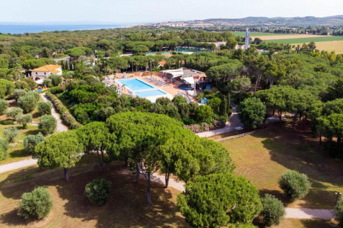 Luftaufnahme eines Mobilheim-Parks mit Pool, viel Grün, umgeben von Bäumen und Aussicht aufs Meer.