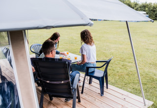Tre persone sedute fuori da una tenda safari al Camping Nommerlayen in Lussemburgo, giocano insieme.