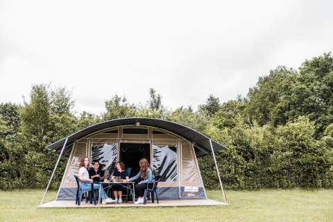 Gruppo si rilassa davanti a una tenda safari al Camping Nommerlayen in Lussemburgo, circondato dal verde.
