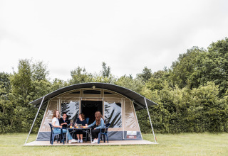 Gruppo si rilassa davanti a una tenda safari al Camping Nommerlayen in Lussemburgo, circondato dal verde.