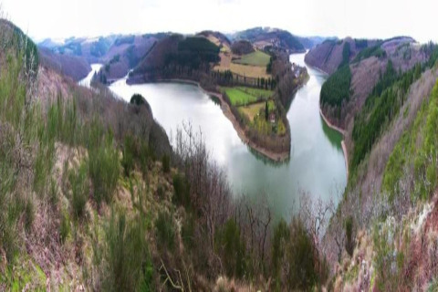 Vue panoramique d'une rivière sinueuse et vallée verdoyante prise depuis un safari-tente, colline environnante.