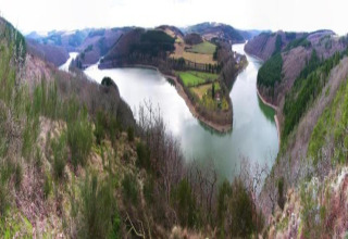 Panoramisch zicht vanuit een safaritent op een slingerende rivier en groene vallei tussen heuvels.