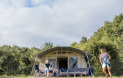 A family enjoys playing badminton in front of a safari tent at Camping Nommerlayen 2 in Luxembourg.
