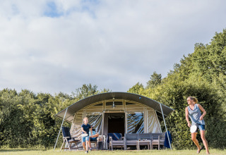 En familie hygger sig med badminton foran et safaritelt på Camping Nommerlayen 2 i Luxembourg.