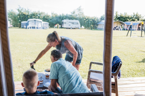 Familie nyder et måltid sammen foran en safaritelte på Camping Nommerlayen 2 i Luxembourg.