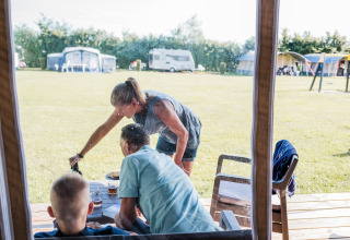 Familie nyder et måltid sammen foran en safaritelte på Camping Nommerlayen 2 i Luxembourg.
