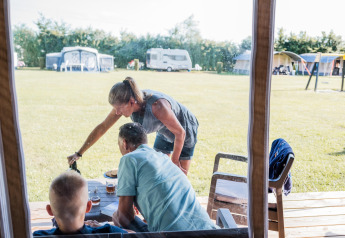A family enjoys an outdoor meal at a safari tent at Camping Nommerlayen 2 in Luxembourg.
