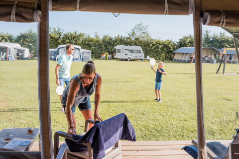 Familia disfrutando de acampar en la tienda safari Camping Nommerlayen 2 en Luxemburgo durante un día soleado.