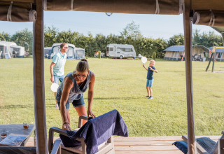 Familie, der nyder camping ved safari-teltet Camping Nommerlayen 2 i Luxembourg på en solrig dag.