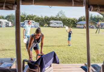 Family enjoying camping at the safari tent Camping Nommerlayen 2 in Luxembourg on a sunny day.