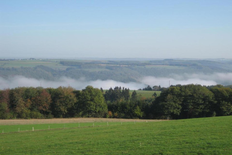 Udsigt fra en safari telt ved Camping Nommerlayen 2 i Luxembourg med grønne marker og let tåge.