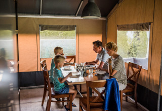 Gezin aan tafel in een safaritent bij Resort Nommerlayen 3 in Luxemburg.