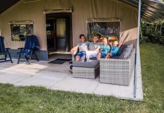 Gezin zit gezellig op een sofa voor een safaritent bij Resort Nommerlayen 3 in Luxemburg.