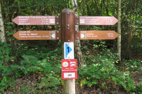 Panneau de sentier au Resort « Nommerlayen 3 » au Luxembourg, indiquant le Mullerthal Trail et des points d’intérêt.