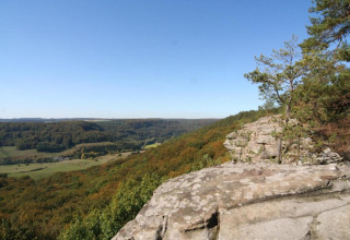 Zicht vanaf safaritent Resort Auf Kengert 1 in Luxemburg met rotsplateau, bomen en heuvelachtig landschap.