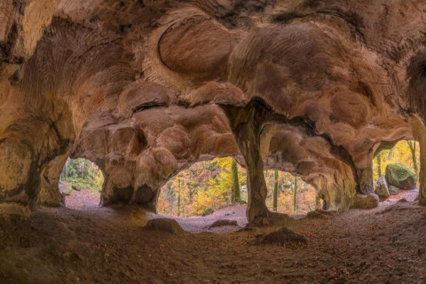 Grotte rocheuse aux formes uniques au Resort Auf Kengert 1 au Luxembourg, vue sur forêt d’automne.