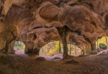 Grotte rocheuse aux formes uniques au Resort Auf Kengert 1 au Luxembourg, vue sur forêt d’automne.