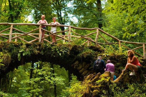 Des personnes admirent la forêt verdoyante sur un pont en bois au Resort Auf Kengert 1 au Luxembourg.