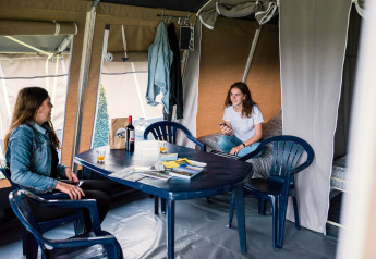 Deux femmes se détendent dans une tente safari au Camping Gritt 1 au Luxembourg, assises à une table.