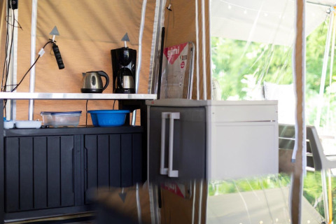 Kleine keukenhoek in een safaritent met koffiezetapparaat, waterkoker, opbergkasten en keukenspullen.