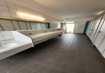 Photo d’une salle de bains partagée moderne dans une tente safari, avec lavabos, miroirs et cabines.