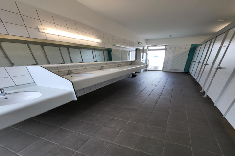 Foto van een modern gedeeld sanitair in een safaritent met wasbakken, spiegels en toilethokjes.