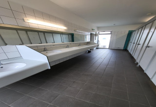 Foto van een modern gedeeld sanitair in een safaritent met wasbakken, spiegels en toilethokjes.