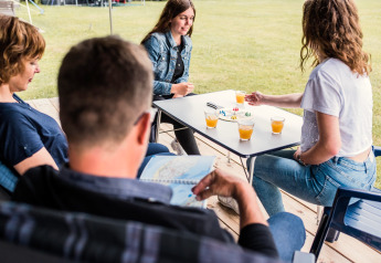 Quatre personnes jouent à un jeu de société et boivent du jus autour d'une table sous une tente safari au Luxembourg.