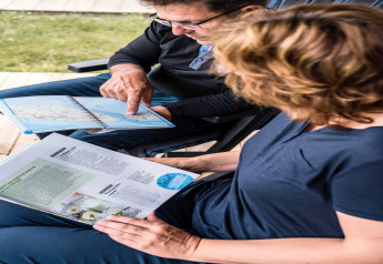 Deux personnes dans une tente safari au Camping Gritt 1 au Luxembourg consultent une carte et une brochure.