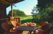 Udendørs spiseplads ved luksus safari telt på Ameland med mad på bordet og udsigt til grøn natur.