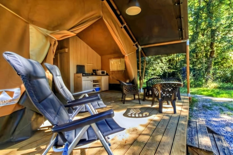 Tienda safari de lujo en Ameland, Países Bajos, con terraza de madera, sillas, mesa y área de cocina.