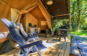 Tienda safari de lujo en Ameland, Países Bajos, con terraza de madera, sillas, mesa y área de cocina.