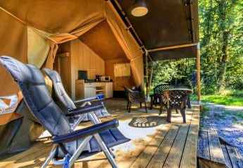 Tienda safari de lujo en Ameland, Países Bajos, con terraza de madera, sillas, mesa y área de cocina.