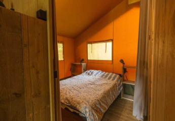 Vista interior de una tienda safari de lujo en Ameland, Países Bajos, con cama doble y decoración acogedora.